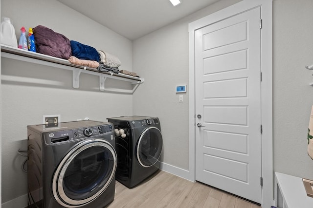 washroom with laundry area, baseboards, light wood finished floors, and washing machine and clothes dryer