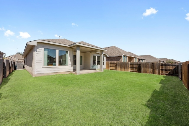 rear view of property featuring a patio area, a fenced backyard, a shingled roof, and a lawn