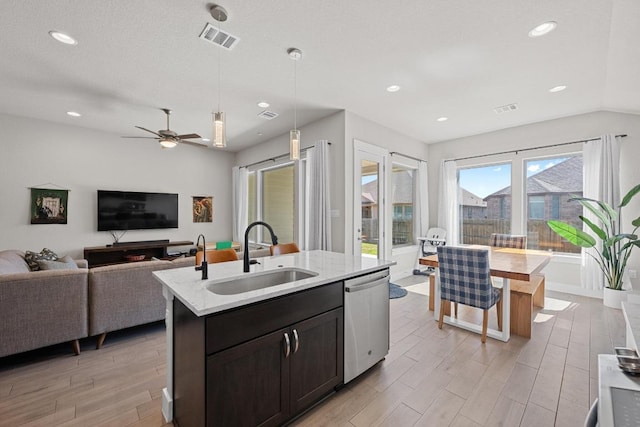 kitchen featuring a sink, visible vents, open floor plan, stainless steel dishwasher, and light wood finished floors