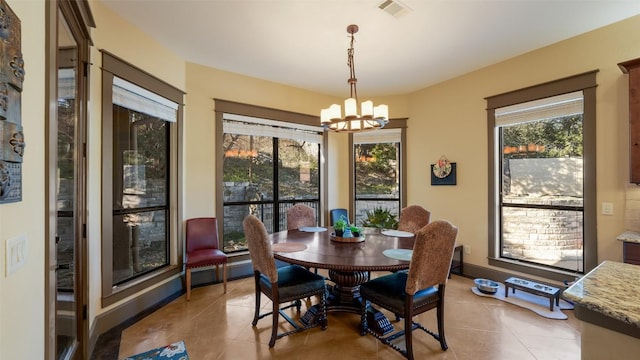 tiled dining space with baseboards, a healthy amount of sunlight, visible vents, and an inviting chandelier