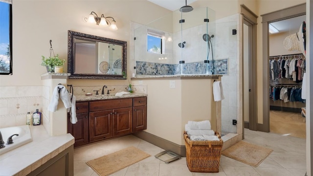 bathroom featuring a stall shower, tile patterned floors, a garden tub, a walk in closet, and vanity