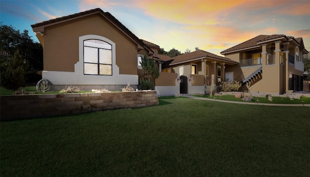 mediterranean / spanish house with a tiled roof, stairway, a lawn, and stucco siding