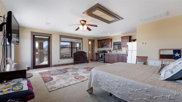 bedroom with access to exterior, freestanding refrigerator, visible vents, and a sink