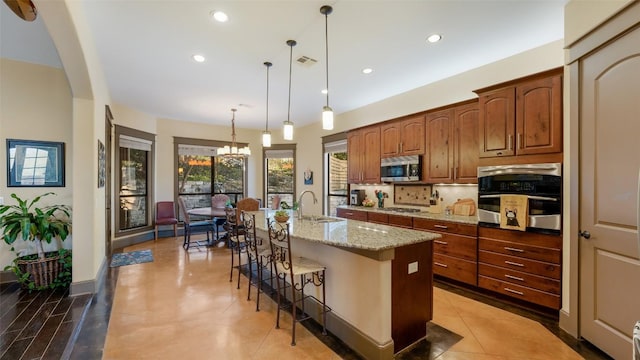 15100 Canary St, Austin, TX 78734 - kitchen with stainless steel appliances, a kitchen breakfast bar, light stone counters, a kitchen island with sink, and recessed lighting