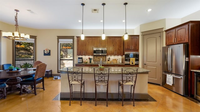 kitchen with tasteful backsplash, visible vents, dark stone counters, appliances with stainless steel finishes, and a kitchen breakfast bar