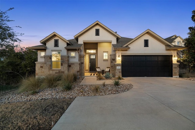 view of front of property featuring a garage, driveway, stone siding, and stucco siding