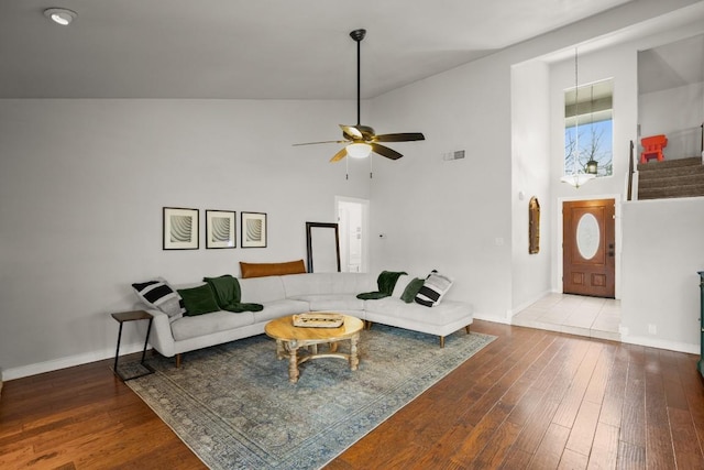 living area with wood-type flooring, a ceiling fan, a high ceiling, and visible vents