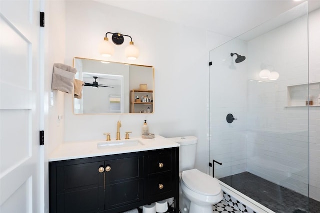 bathroom with toilet, a ceiling fan, tiled shower, and vanity