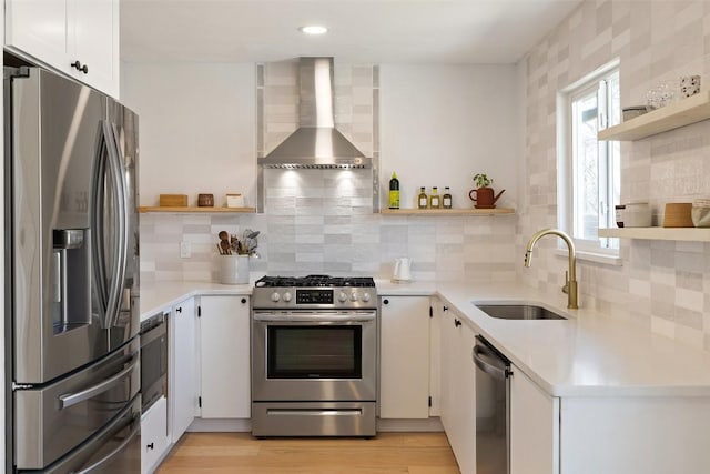 kitchen with wall chimney exhaust hood, appliances with stainless steel finishes, open shelves, and a sink