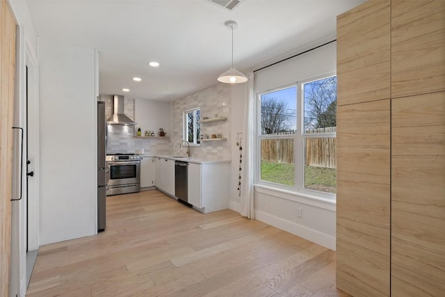 kitchen featuring appliances with stainless steel finishes, light countertops, wall chimney range hood, open shelves, and backsplash