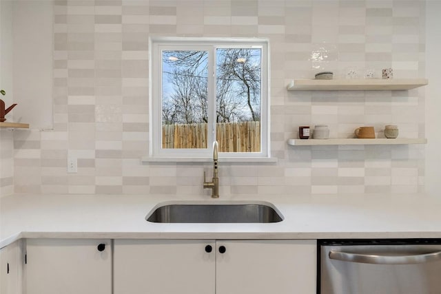 kitchen featuring light countertops, stainless steel dishwasher, white cabinetry, open shelves, and a sink