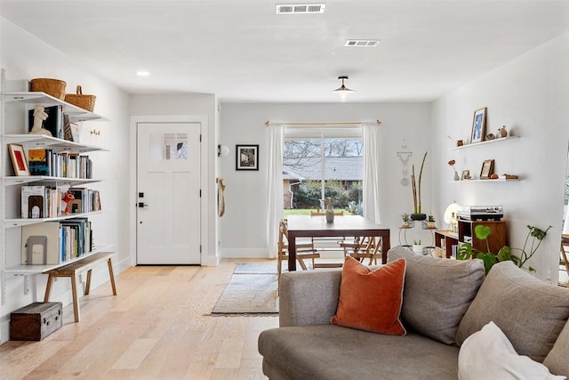 foyer entrance featuring light wood finished floors, visible vents, and baseboards