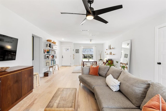 living room with light wood finished floors, visible vents, and a ceiling fan