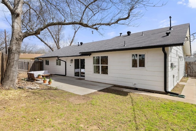 back of property with fence private yard, a patio area, a shingled roof, and a lawn