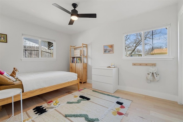 bedroom featuring a ceiling fan, light wood-style flooring, and baseboards