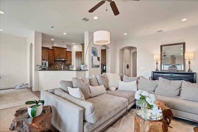 living area with arched walkways, ceiling fan, visible vents, and recessed lighting