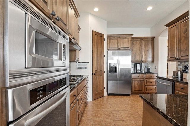 kitchen with light tile patterned flooring, recessed lighting, stainless steel appliances, decorative backsplash, and dark stone countertops