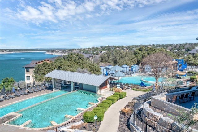 community pool featuring a water view, fence, and a patio