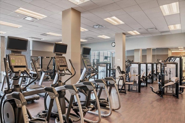 exercise room with a paneled ceiling, wood finished floors, and visible vents