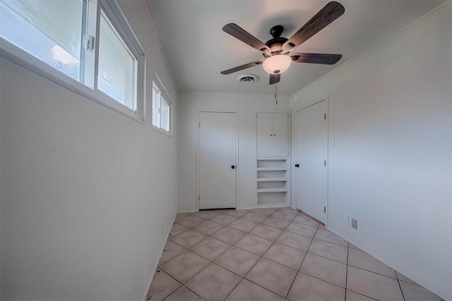 spare room with a ceiling fan, visible vents, and light tile patterned flooring