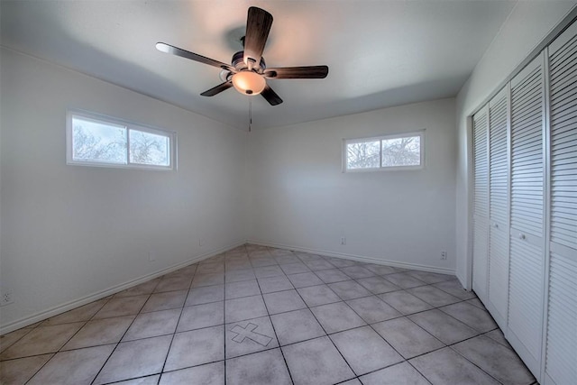 unfurnished bedroom with a closet, multiple windows, ceiling fan, and baseboards