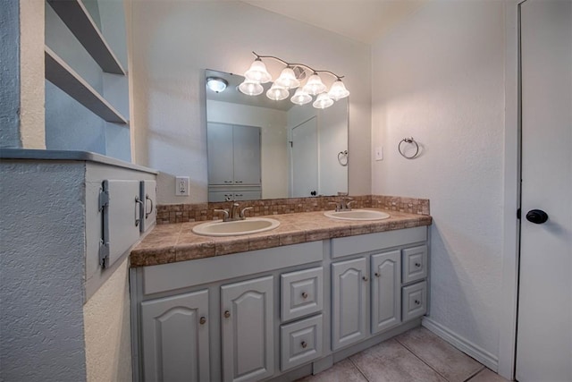 bathroom featuring double vanity, baseboards, a sink, and tile patterned floors