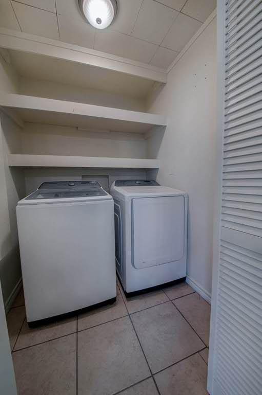 laundry area with light tile patterned floors, baseboards, and washer and dryer