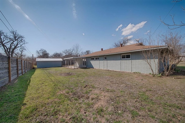 rear view of property with an outbuilding, brick siding, a yard, and a fenced backyard