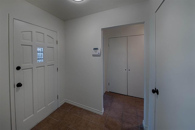 entryway with dark tile patterned flooring and baseboards