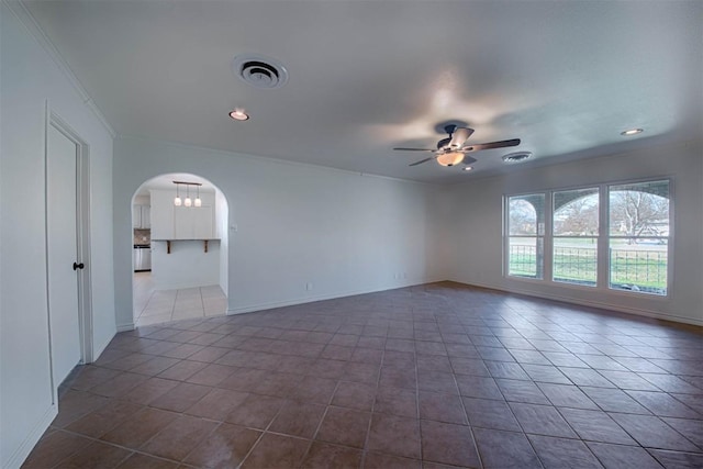 tiled empty room with arched walkways, visible vents, ceiling fan, and baseboards