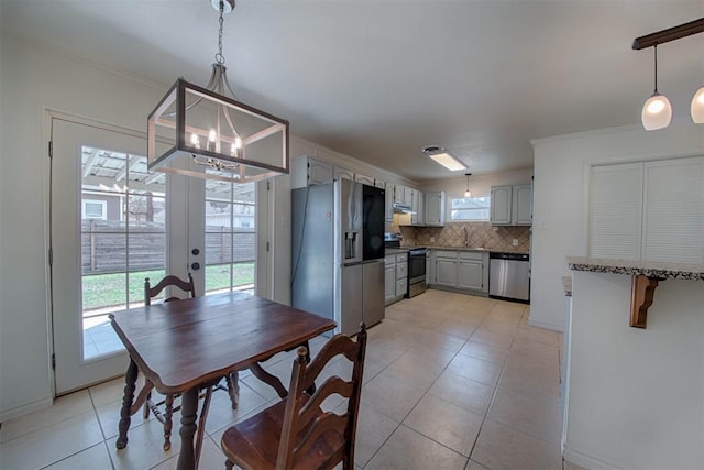 dining room with a chandelier, french doors, crown molding, and light tile patterned floors