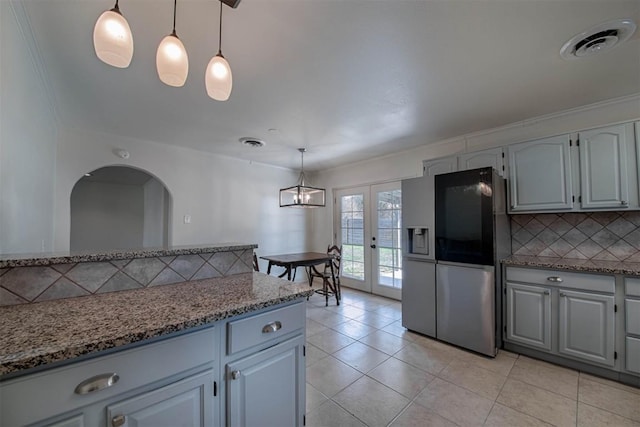 kitchen featuring tasteful backsplash, stainless steel refrigerator with ice dispenser, visible vents, and light stone countertops