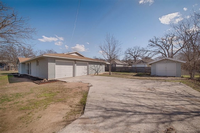 exterior space with driveway, brick siding, an attached garage, and fence