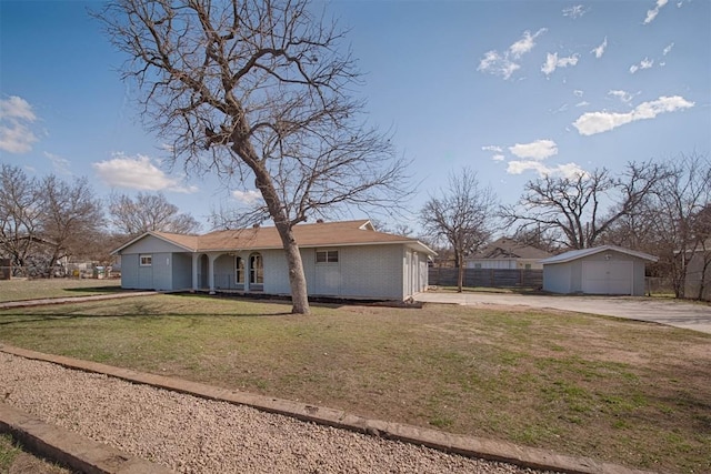 view of front of home with an outdoor structure, fence, a front lawn, and brick siding