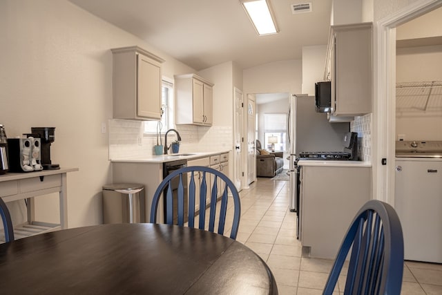 kitchen with lofted ceiling, a sink, visible vents, light countertops, and washer / clothes dryer