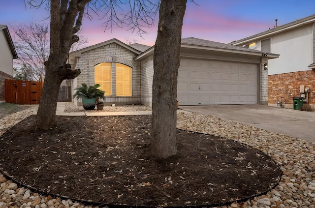 view of front facade featuring a garage, fence, concrete driveway, and brick siding