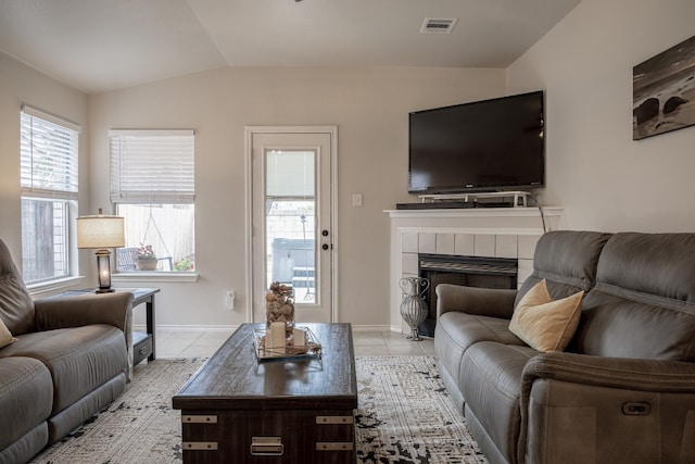 living area featuring lofted ceiling, light tile patterned floors, baseboards, and a tile fireplace