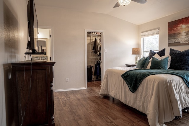 bedroom with baseboards, dark wood finished floors, a ceiling fan, lofted ceiling, and a walk in closet