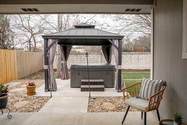 view of patio / terrace with visible vents, a fenced backyard, a hot tub, and a gazebo