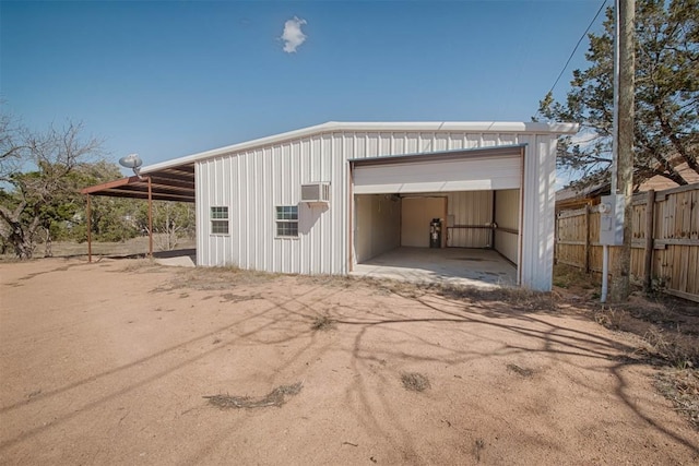 garage featuring a garage, an AC wall unit, and fence