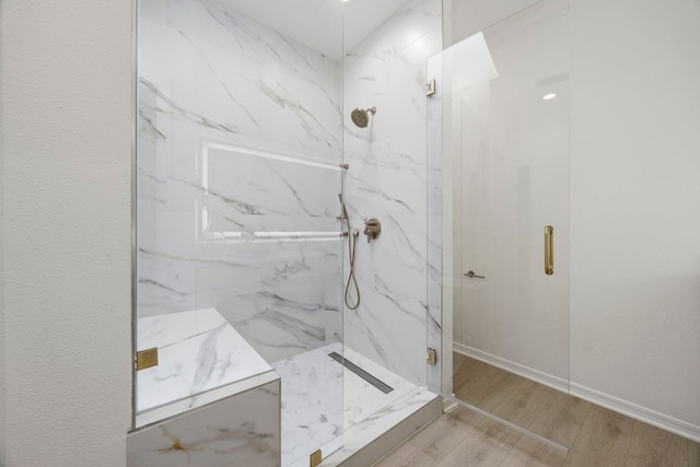 bathroom featuring a marble finish shower, baseboards, and wood finished floors