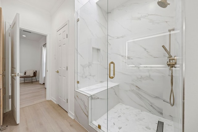 full bathroom featuring a marble finish shower, ornamental molding, and wood finished floors