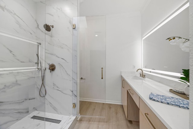 full bathroom with a marble finish shower, ornamental molding, wood finished floors, and vanity