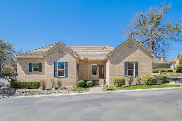 view of front of house featuring a tile roof and brick siding