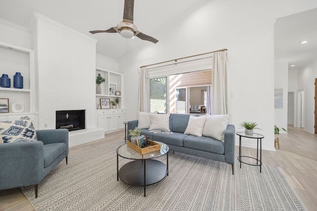 living room with light wood-type flooring, baseboards, ornamental molding, and a fireplace with raised hearth