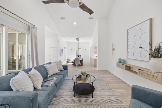 living area featuring high vaulted ceiling, light wood finished floors, visible vents, and a ceiling fan