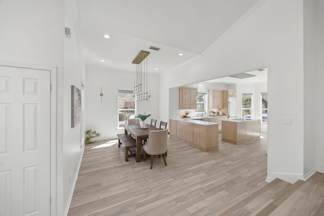 dining area with high vaulted ceiling, light wood-type flooring, and visible vents