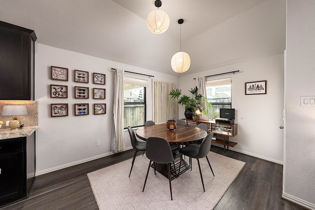 dining area with dark wood-type flooring, lofted ceiling, and baseboards