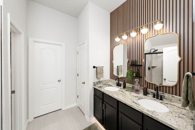 bathroom featuring a sink, a shower stall, baseboards, and double vanity