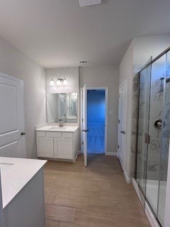 bathroom featuring a shower stall, wood finished floors, and vanity